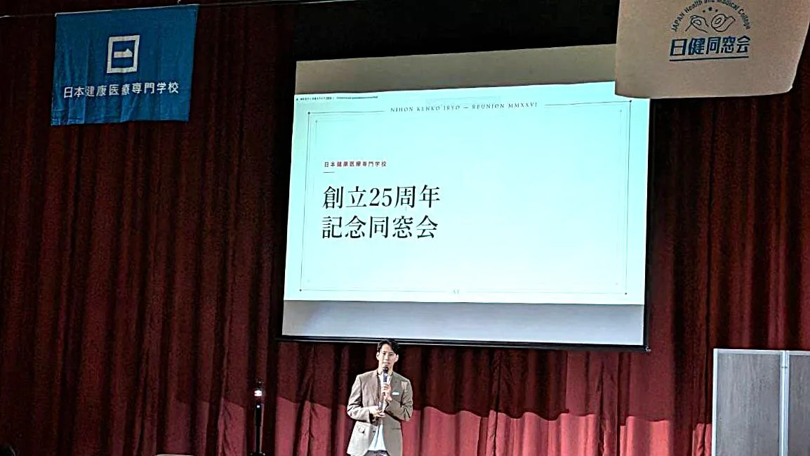 「創立25周年記念同窓会」のスライドの前で話す登壇者