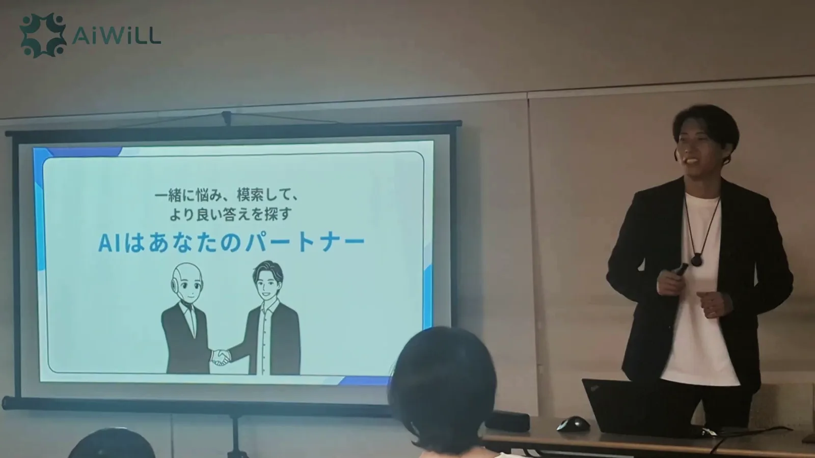 スクリーンの前で説明する講師